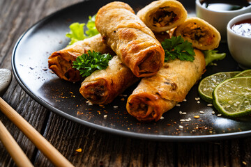 Spring rolls and sauces on wooden table
