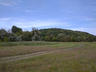 View of a mountain with trees growing on it. Below the mountain there is a plain - lakes and a river.