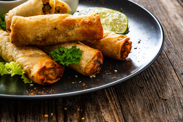 Spring rolls and sauces on wooden table
