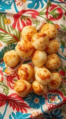 A bunch of small, golden brown balls are sitting on a red and blue cloth. The cloth has a floral pattern and the balls are arranged in a neat pile