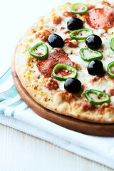 Pizza with salami, jalapeno pepper and black olives. Home made food. Concept for a tasty and hearty meal. Close up.	