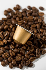 Golden coffee capsule on coffee beans on a white background. Advertising