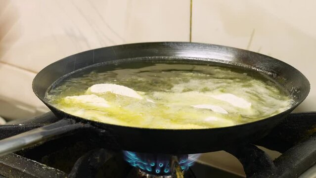 fish frying in oil in a pan, close-up