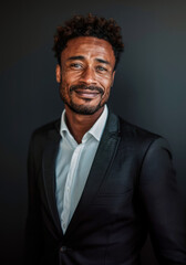 Fototapeta premium A man in a black suit and white shirt standing in front of a dark background.