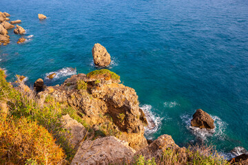 Rock formations along the coastline of the deep. blue waters of the Mediterranean Sea in Antalya, Turkey; copy space