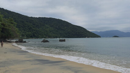 Romantic couple walking along tropical beach shoreline