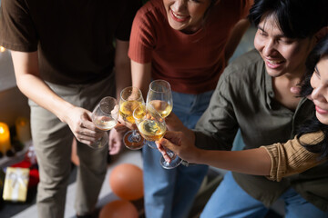 Close up hand holding glass. Group of young asian people smiling friends drinking at birthday party toast with beer. food and beverag