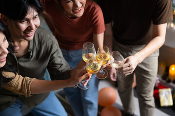 Close up hand holding glass. Group of young asian people smiling friends drinking at birthday party toast with beer. food and beverag