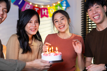 friend birthday cake. young asian woman blows out a birthday cake that friends brought for a birthday party. celebrating Birthday party. Group of friends smiling enjoying party