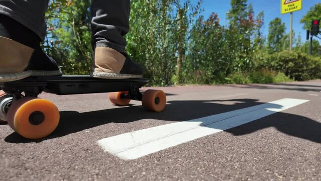 Person riding a small electric longboard through the city, focusing on wheels and feet. Urban sustainable and eco-friendly mobility. Zero emissions