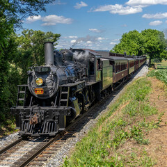 Strasburg Railroad underway with passenger cars with blue sky and clouds