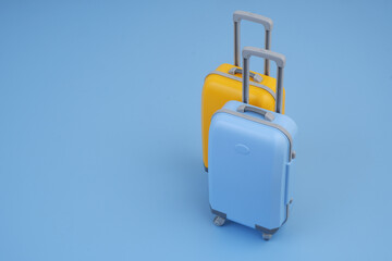 Orange and blue travel suitcase on blue background. Copy space for text.	