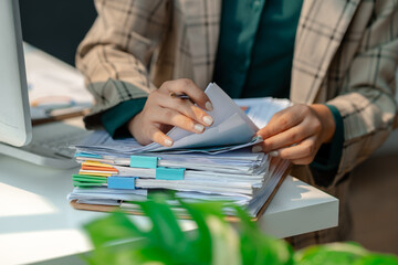 a secretary is organizing stack of paperwork for keep her desk clean, tidy up all finance document...