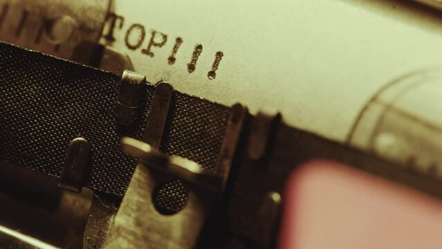 Analog typewriter printing word Stop with three exclamation marks on paper page. Extreme close-up shot
