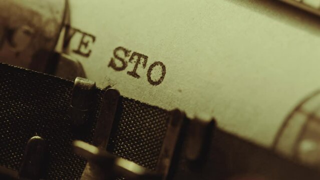 Printing Love Story phrase on paper with vintage manual typewriter while starting new romance novel. Extreme close-up view