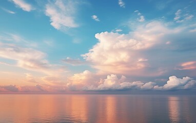 Obraz premium Serene sunrise over a calm ocean with fluffy clouds reflecting in the water.