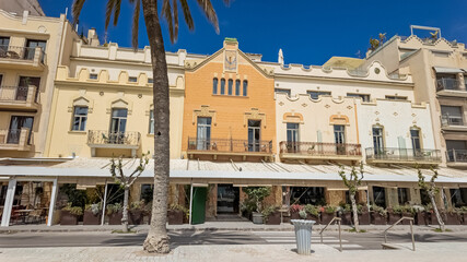 Sunny Mediterranean promenade with charming pastel-colored buildings and palm trees, ideal for travel and holiday-related themes