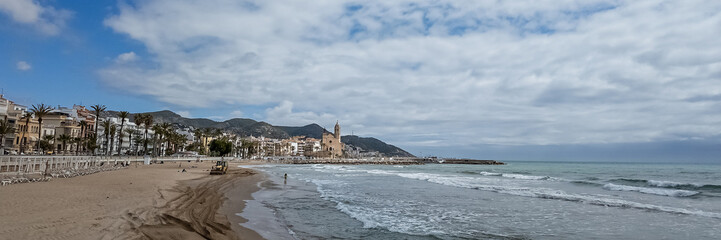 Tranquil Mediterranean beach with palm trees and historical buildings in a European seaside town, ideal for travel and summer holiday concepts