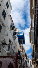 Narrow European alley with traditional white buildings and a vivid blue balcony under a clear sky, ideal for travel and architecture themes
