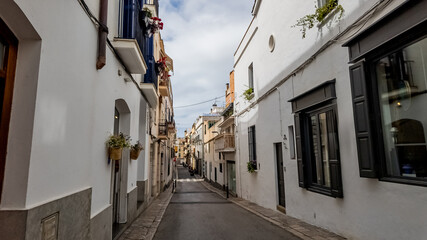 Traditional Mediterranean street with white walls and potted plants, typical of Spanish festivals like Fiestas de San Juan -- ideal for travel and culture themes