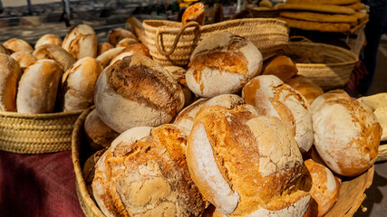 Freshly baked artisan bread loaves in wicker baskets at an outdoor market, related to concepts of organic food and holidays like Thanksgiving