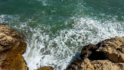 Aerial view of turbulent sea waves crashing against rugged cliffs, ideal for travel themes and World Oceans Day awareness campaigns