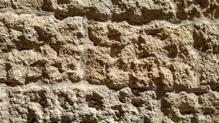 Textured coarse sandstone wall background under natural light, suitable for geology, archaeology, or construction-related concepts