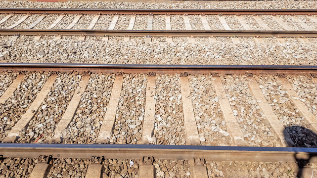 Parallel railroad tracks with textured gravel beds under bright daylight, ideal for concepts like travel, transportation, and industrial infrastructure