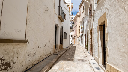 Obraz premium Traditional sunny European alley with white-washed buildings, ideal for travel and real estate themes, especially related to Mediterranean lifestyle and culture