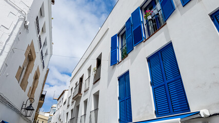 Mediterranean architecture with vibrant blue shutters on white buildings under a clear blue sky,...
