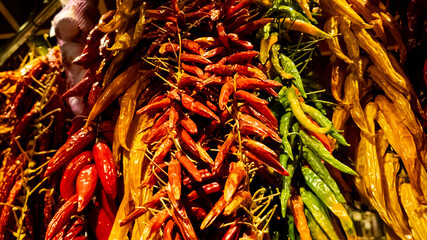 Assorted hanging dried red and green chili peppers at a spice market, capturing the essence of culinary traditions and fiery flavors