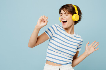 Young singer woman she wear striped t-shirt casual clothes listen to music in headphones sing song...