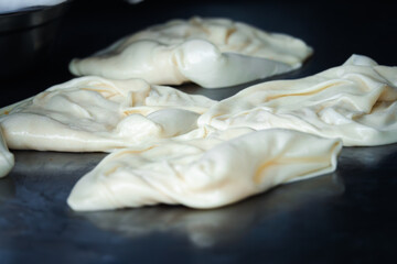 A few pieces of dough are spread out on a counter