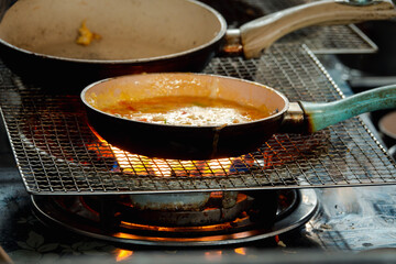 A pan of food is cooking on a stove with a metal handle