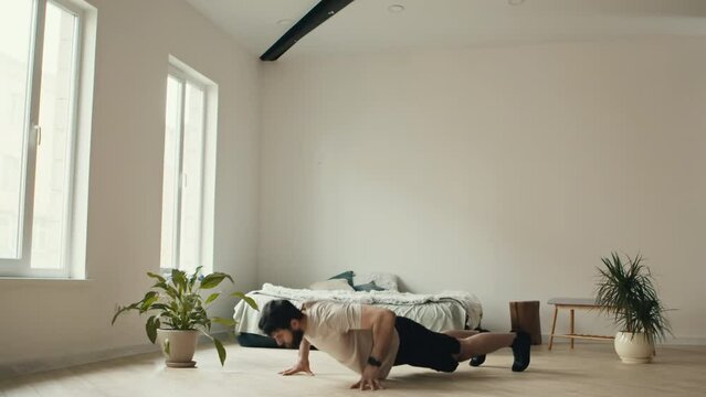 High-intensity interval training. Young man practicing burpee exercise at home