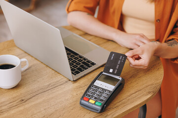 Close up woman hold bank payment terminal to process acquire credit card pay bill sitting alone at...