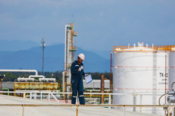 Fototapeta premium one Asian male industrial engineers use a top roof visual tank view of the new installation and crude oil storage tank