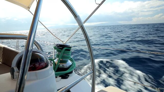 View through the steering wheel and sea compass to the waves rushing along the side of a sailing yacht. Yacht trip stock video in HD quality