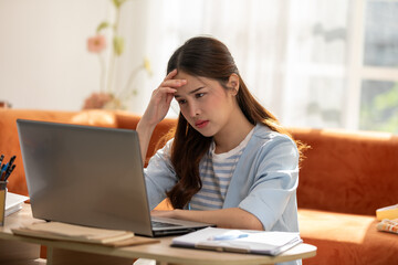 Asian Woman Experiencing Stress While Working on Laptop at Home