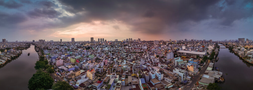 Urban density along canal. Dramatic aerial panorama of Ho Chi Minh City, Vietnam showing rooftops and skyline in evening light.

