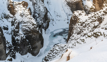 Top view in the famous Icelandic Fjadrargljufur, Fjaðrárgljúfur canyon during winter. Snowy canyon, frozen river in the canyon. Famous must-see touristic spot. Wonderful Icelandic landscape.
