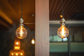 A classic designed tungsten lightbulb is glowing in orange warmlight shade with blurred background...
