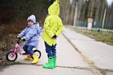 Toddler girl on balance bike with her brother