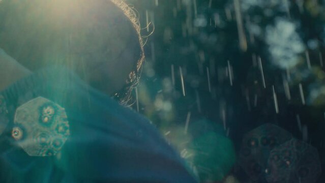 Woman in a rain coat standing outside and feeling rain drops