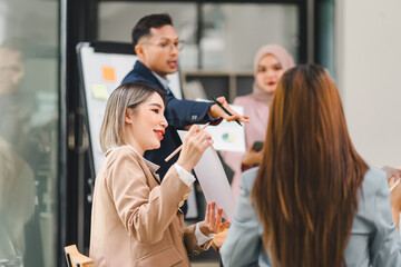 Diverse business team analyzing data and discussing strategies during an office meeting, using documents and a laptop.