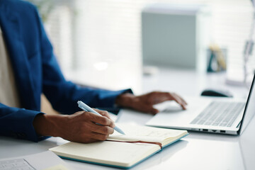 Hands of businessman writing in planner at desk