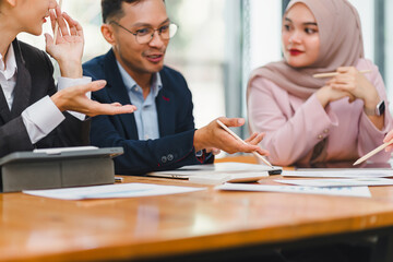 Diverse business team collaborates and analyzes reports during meeting, highlighting teamwork and strategic planning in modern office.