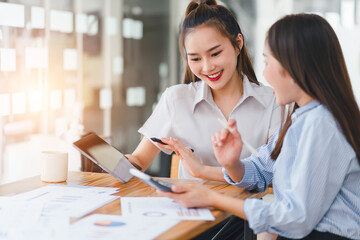 Fototapeta premium Two businesswomen reviewing and discussing data charts during meeting in modern office.