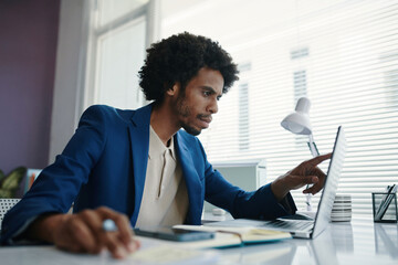 Serious businessman checking table on laptop screen