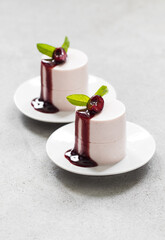 Cherry Cream pudding  cylindrical shape. With cherry sauce. On a plate. Light gray background